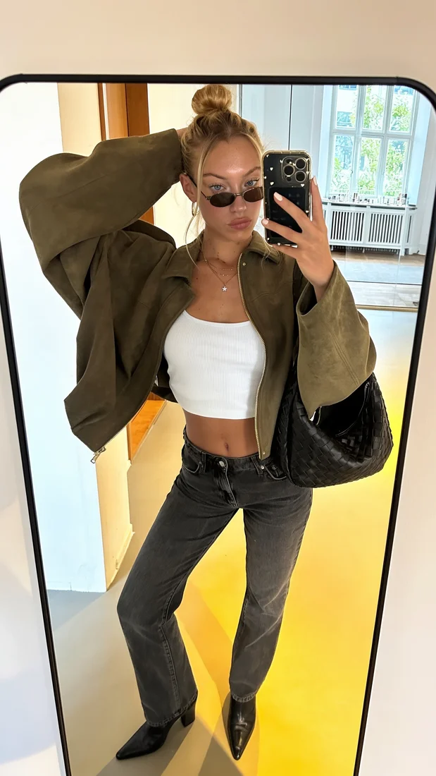 Avatar one taking a mirror selfie in a green jacket and white top